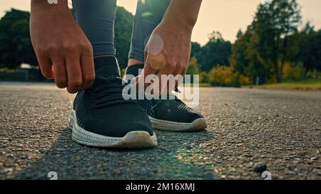 Sportlerin Läufer schlanker Lauf-Marathon in schwarzen sportlichen Sneakers im Freien stoppen Schnürsenkel auf Schuhe binden. Sportliche, weibliche motivierte Konkurrentin Stockfoto