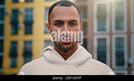 American Latino Mann gut aussehend männlich sportlich muskulösen Kerl ernsthaft Blick auf Kamera Stand auf Stadt Straße nickend Kopf Unterstützung Idee Genehmigung Geste a Stockfoto