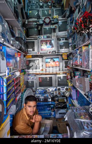 Kleiner Stromeinzelhändler, der Fernseh- und Audiogeräte zum Verkauf in der Medina von Essaouira, Marokko, verkauft. Nordafrika. Männlich Stockfoto