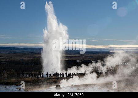 Allgemeiner Blick auf den Geysir Strokkur im geothermischen Park Haukadalur. Die geothermische Region in der Nähe des Flusses Hvitá und der Stadt Reykjavík beherbergt den geothermischen Park Haukadalur. Hier befindet sich Strokkur, einer der berühmtesten Geysire Islands, der im Durchschnitt alle 4 bis 8 Minuten ausbricht, mit einer durchschnittlichen Höhe von 15 bis 20 Metern, manchmal bis zu 40 Meter. Im Park gibt es mehrere geothermische Merkmale wie Schlammbecken, Fumarolen, Algenablagerungen und andere Geysire daneben und um ihn herum. Stockfoto