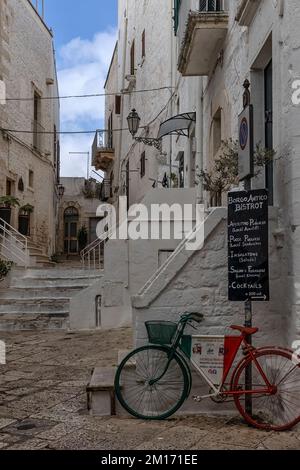 OSTUNI, ITALIEN - 18. OKTOBER 2022: Altes Fahrrad mit Anzeige für Restaurant in der Altstadt Stockfoto