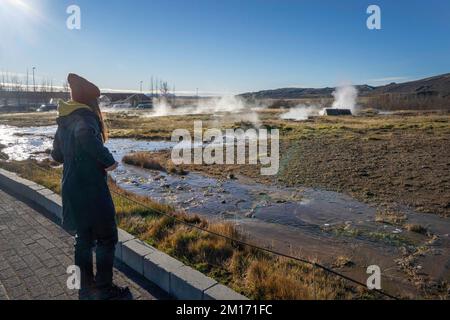 Reikiavik, Island. 21.. Okt. 2022. Ein Tourist beobachtet die Fumarolen im geothermischen Park Haukadalur in Reykjavik. Die geothermische Region in der Nähe des Flusses HvitÃ und der Stadt ReykjavÃ-k beherbergt den geothermischen Park Haukadalur. Hier befindet sich Strokkur, einer der berühmtesten Geysire Islands, der im Durchschnitt alle 4 bis 8 Minuten ausbricht, mit einer durchschnittlichen Höhe von 15 bis 20 Metern, manchmal bis zu 40 Meter. Im Park gibt es mehrere geothermische Merkmale wie Schlammbecken, Fumarolen, Algenablagerungen und andere Geysire daneben und um ihn herum. (Bild: © Jorge Castellanos/S Stockfoto