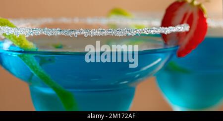 Zwei Gläser mit blauem margarita-Cocktail, garniert mit Limettenschale und Erdbeeren, selektiver Fokus. Stockfoto