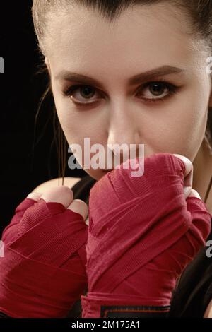 Muay Thai Boxerin in Angriffsstellung. Fitness junge Frau Boxtraining auf schwarzem Hintergrund Stockfoto