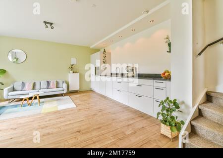 Ein Wohnzimmer mit Holzfußboden und weißen Schränken auf beiden Seiten der Treppe, die in die zweite Etage führt Stockfoto