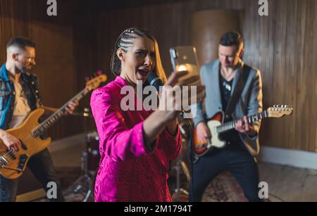 Freigestellte Aufnahme einer Musikband, die ein Selfie mit einem Telefon auf Wiederholung macht, junges Bandkonzept. Hochwertiges Foto Stockfoto