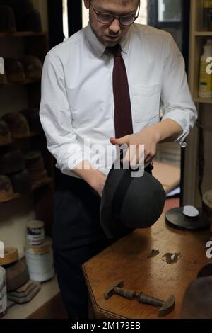 Ein Mitarbeiter von Lock & Co Hatters formte einen Hut um, London, Großbritannien. Stockfoto