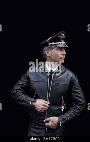 Rocker in Café Racer-Ausrüstung mit schwarzer Lederjacke und Servicehut Stockfoto