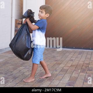 Zeit, den Müll zu entsorgen. Aufnahme eines kleinen Jungen, der den Müll zu Hause herausnimmt. Stockfoto