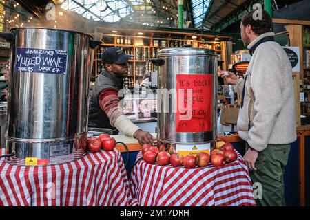 London, Großbritannien. 08.. Dezember 2022. Glühwein ist während der aktuellen Kälteperiode gefragt. Festliche Einkäufer, Besucher und Touristen drängen sich in die Markthallen des Borough Market, um Kunsthandwerk zu kaufen und einen Glühwein und andere saisonale Angebote zu genießen. Kredit: Imageplotter/Alamy Live News Stockfoto