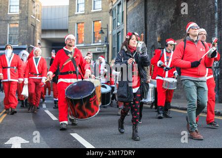 London, Großbritannien. 08.. Dezember 2022. Die Santas machen einen Spaziergang durch den Borough Market und entlang der Themse am South Bank of London. Hunderte fröhlicher Santas nehmen an der 2022. Ausgabe der London SantaCon Teil, einer jährlichen, gemeinnützigen Tagung, bei der die heutigen Geber Lapplands auf verschiedenen Routen in London wandern, die normalerweise am Trafalgar Square zusammenlaufen. Der Spaziergang bringt Geld für wohltätige Zwecke ein. Die diesjährige SantaCon ist nach mehrjähriger Abwesenheit während der Covid-Pandemie kleiner und weniger aufwändig als die Vorjahre. Kredit: Imageplotter/Alamy Live News Stockfoto