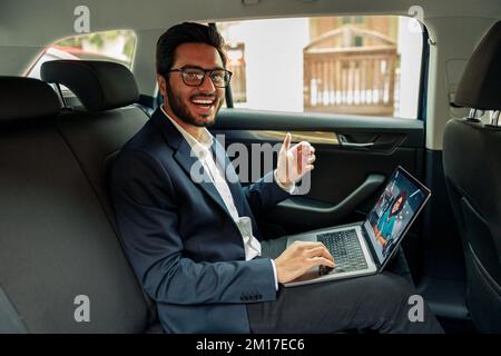 Ein Geschäftsmann hält per Videoanruf ein Geschäftstreffen ab, während er mit dem Auto zum Büro fährt Stockfoto