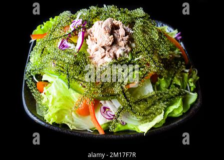 Frischer vietnamesischer Salat mit Gemüse, Thunfisch und Meerestrauben auf schwarzem Hintergrund, Draufsicht Stockfoto