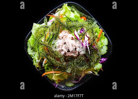 Frischer vietnamesischer Salat mit Gemüse, Thunfisch und Meerestrauben auf schwarzem Hintergrund, Draufsicht Stockfoto