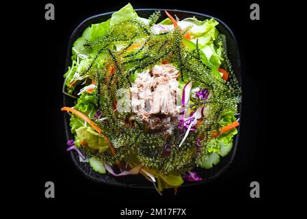 Frischer vietnamesischer Salat mit Gemüse, Thunfisch und Meerestrauben auf schwarzem Hintergrund, Draufsicht Stockfoto