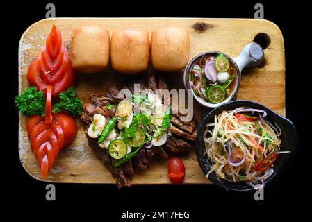 Gegrilltes thailändisches Rindfleisch mit Papayasalat, vietnamesischen Brötchen und Kumquat-Sauce mit Blick von oben Stockfoto