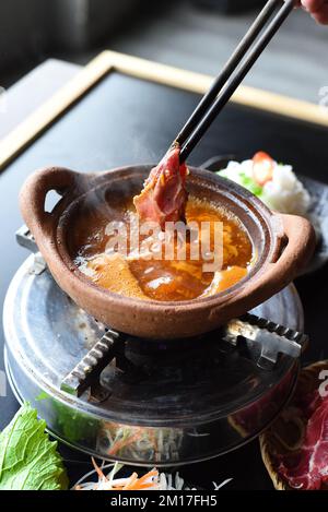 Traditionelles koreanisches Hot-Pot-Gericht mit Rindfleisch und scharfem Bouillon auf schwarzem Tisch Stockfoto