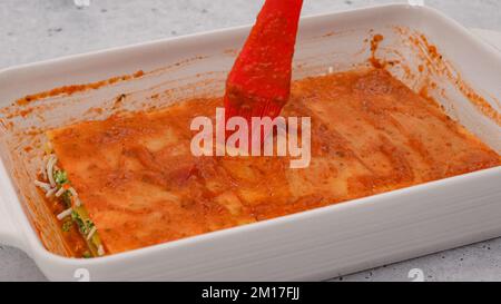 Lasagne zusammenbauen. Die letzte Lasagne mit Marinara-Sauce überziehen. Rezept für Spinat-Lasagne Stockfoto