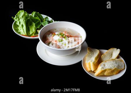 Traditionelle vietnamesische Suppe Pho mit Meeresfrüchten auf schwarzem Hintergrund Stockfoto