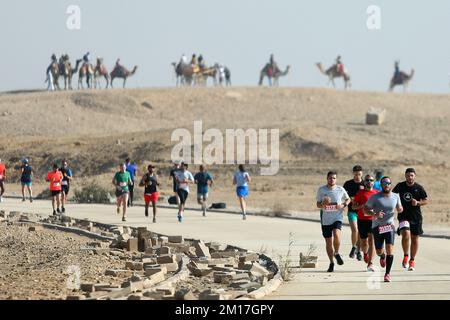 Kairo, Ägypten. 10.. Dezember 2022. Läufer nehmen am Pyramiden-Halbmarathon Teil, der am 10. Dezember 2022 in Gizeh, Ägypten, an der Pyramiden von Gizeh stattfindet. Mit den großen Pyramiden von Gizeh im Hintergrund traten fast 4.000 Läufer aus Dutzenden von Ländern am Samstag bei der vierten Ausgabe des Pyramiden-Halbmarathons im Südwesten von Kairo, der Hauptstadt Ägyptens, an. Kredit: Ahmed Gomaa/Xinhua/Alamy Live News Stockfoto