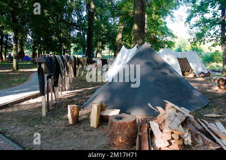 Unschärfe-Zelte auf dem Geschichtsfestival. Militär-Camping in einem Rastplatz. Eine Zeltstadt mit vielen Zelten. Auf einem grünen Rasen im Wald. Viele Stockfoto