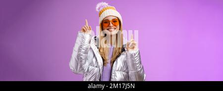 Freudig energetisiert unterhalten nette blonde Frau mit Spaß genießen Sie Urlaub Verschneite Bergtour trägt Sonnenbrille Silber Jacke Winter Hut tanzen Stockfoto