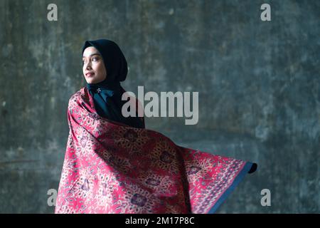 Schöne Frau in schwarzem Hijab in Batik aus Jambi, Indonesien. Stockfoto