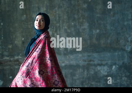 Schöne Frau in schwarzem Hijab in Batik aus Jambi, Indonesien. Stockfoto