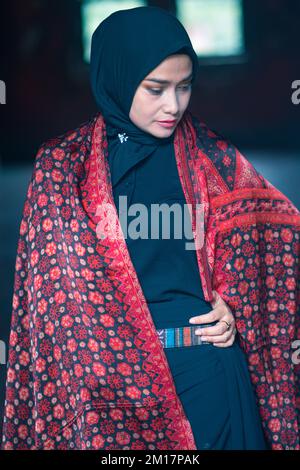 Schöne Frau in schwarzem Hijab in Batik aus Jambi, Indonesien. Stockfoto