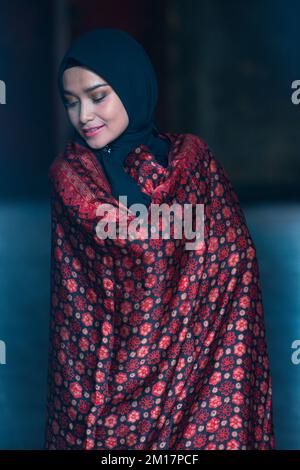Schöne Frau in schwarzem Hijab in Batik aus Jambi, Indonesien. Stockfoto