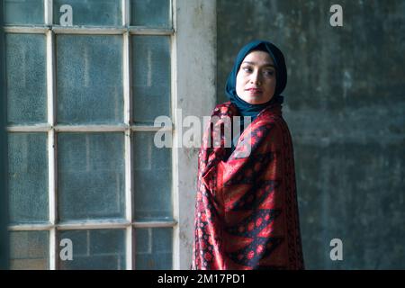 Schöne Frau in schwarzem Hijab in Batik aus Jambi, Indonesien. Stockfoto