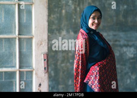 Schöne Frau in schwarzem Hijab in Batik aus Jambi, Indonesien. Stockfoto