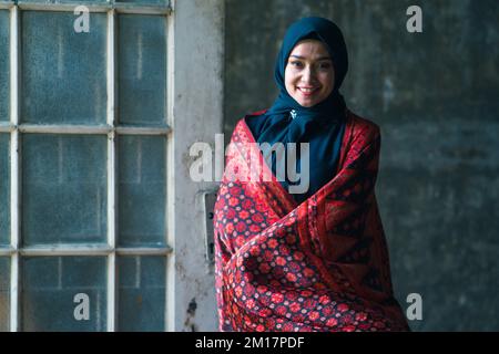 Schöne Frau in schwarzem Hijab in Batik aus Jambi, Indonesien. Stockfoto
