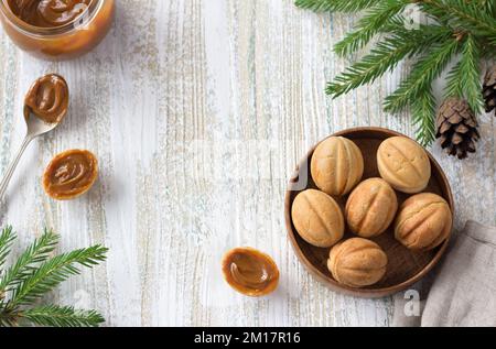 Traditionelles russisches hausgemachtes süßes Gebäck, Shortbread-Nüsse mit gekochter Kondensmilch in einer Holzschüssel auf Holzhintergrund, dekoriert mit Christus Stockfoto