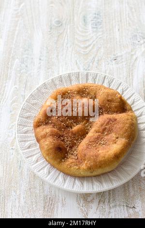 Hausgemachtes gebratenes Navajo-Brot oder süße Elefantenohren mit braunem Zucker und Zimt auf einem Holztisch, selektiver Fokus Stockfoto