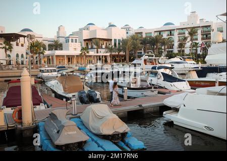 Ein Paar macht einen romantischen Spaziergang bei Sonnenuntergang im Park Hyatt Golf und Yacht Club Marina. Außenansicht eines mediterranen Luxushotels in Dubai, Vereinigte Arabische Emirate. Stockfoto