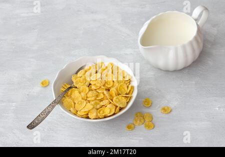 Süße knusprige Cornflakes auf einem grauen strukturierten Hintergrund. Schnell leckeres Frühstück, Blick von oben, freier Platz, horizontal Stockfoto