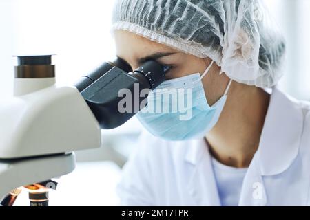 Nahaufnahme des weiblichen Wissenschaftlers im Mikroskop während der Arbeit im medizinischen Labor Stockfoto