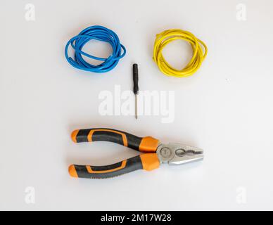 Blaue und gelbe Kabel mit Werkzeugen auf weißem isoliertem Hintergrund Stockfoto