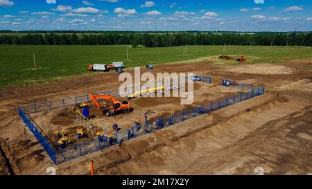 Bagger mit Luftaufnahme und Bauarbeiter, die auf der Baustelle im Freien arbeiten. Rohrverlegung im Graben zur Vergasung. Top-Punkt der Aufnahme. Reparatur und Wiederherstellung der Erdgasversorgung. Stockfoto