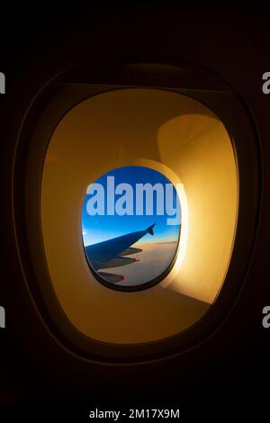 Gelbes Fenster eines Flugzeugs mit blauem Himmel im Hintergrund. Stockfoto