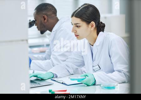 Side-View-Porträt einer jungen Frau aus dem Nahen Osten, die in der medizinischen Forschung im Labor arbeitet Stockfoto