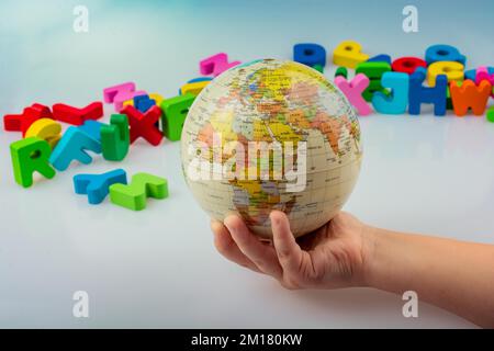 Kleines Modell gobe in Hand mit bunten Buchstaben hinter Stockfoto