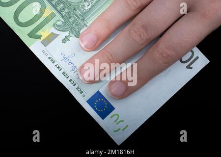 Hand mit 100 Euro Bargeld isoliert auf schwarzem Hintergrund Stockfoto