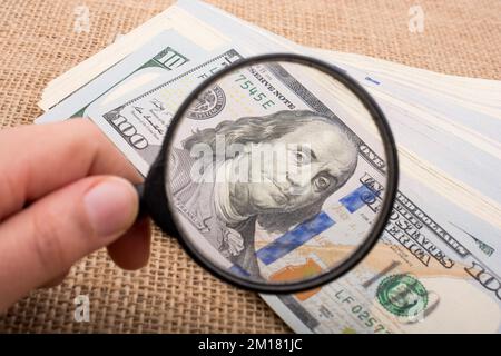 Lupe wird über die Banknote Bündel von US-Dollar gehalten. Stockfoto