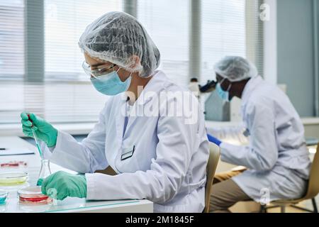 Side-View-Porträt einer Wissenschaftlerin, die Experimente im medizinischen Labor durchführt Stockfoto