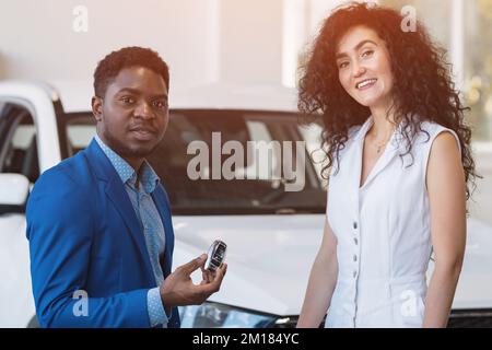 Ein afroamerikanischer Händler gibt dem Kunden den Autoschlüssel Stockfoto