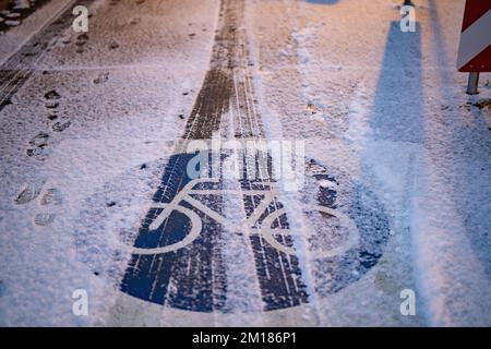 Bad Homburg, Deutschland. 11.. Dezember 2022. Autospuren können im frisch gefallenen Schnee bei Sonnenaufgang auf einer Fahrradspur am Stadtrand von Bad Homburg gesehen werden. Kredit: Frank Rumpenhorst/dpa/Alamy Live News Stockfoto