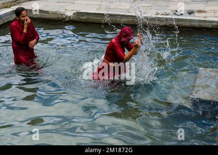 Zwei weibliche Pilger haben eine Dusche zur Reinigung von Körper und Seele durch die Ausführung durch die 108 heiligen Brunnen Stockfoto