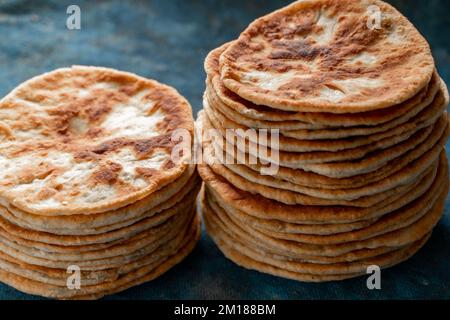 Fladenbrot Lavash, Chapati, Naan, ein Haufen Tortilla auf blauem Hintergrund hausgemachtes Fladenbrot gestapelt. Stockfoto